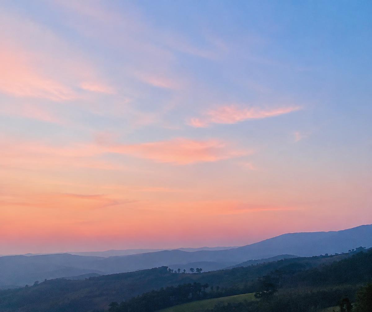 A soft pink and blue dawn sky over quiet hills